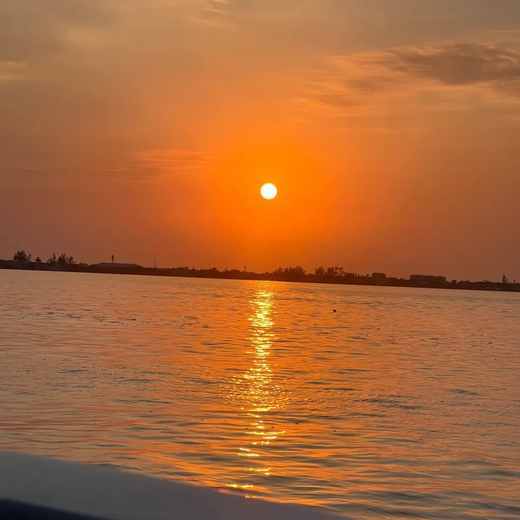 A breathtaking Anna Maria Island sunset with vibrant orange and pink skies over the Gulf of Mexico, inviting tourists to experience Florida's natural beauty.